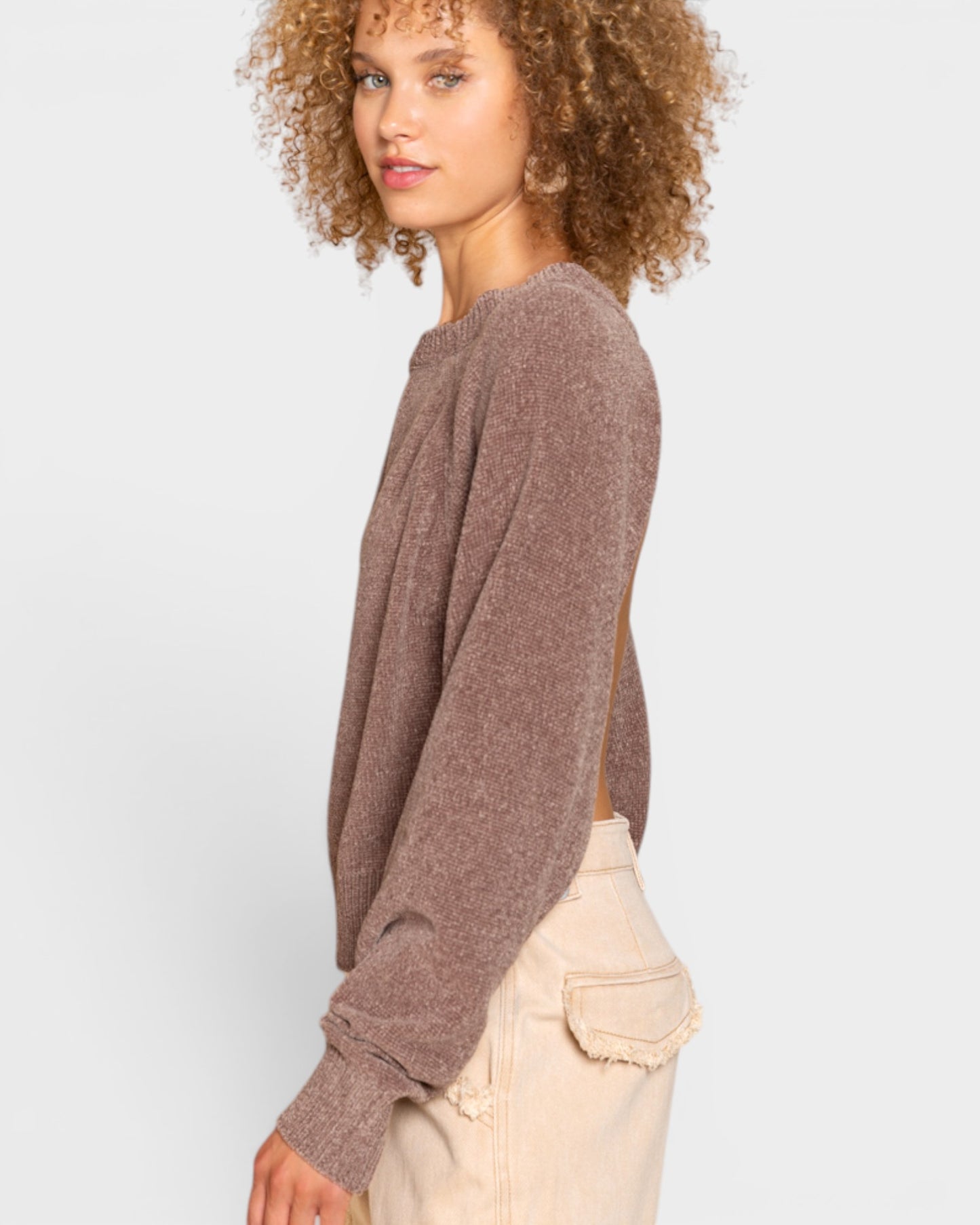 Woman wearing a brown sweater and beige pants on a white background
