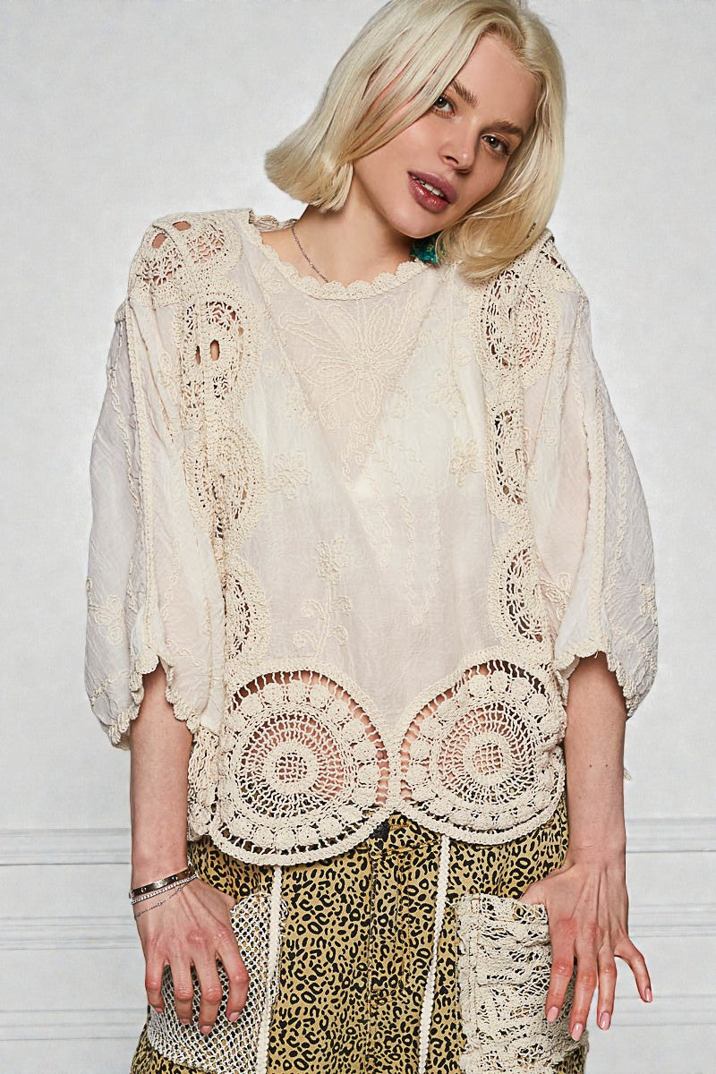 Woman wearing a cream lace top with a white background