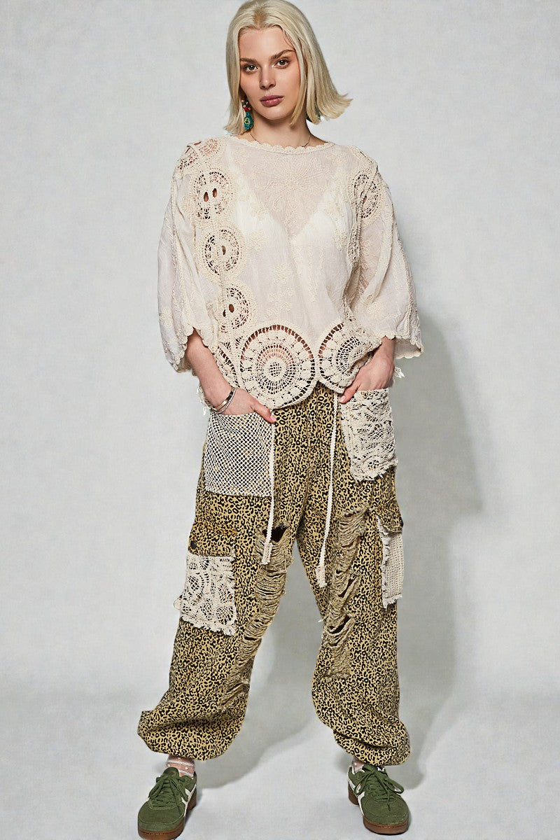 Woman wearing a cream-colored top and patterned pants on a white background