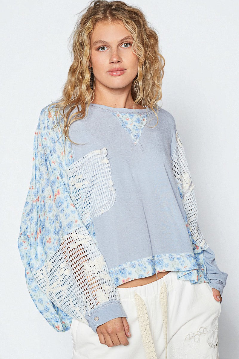 Woman wearing a light blue sweater with floral patterns on a white background