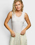 Woman wearing a white lace tank top and light-colored skirt against a plain background