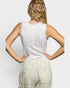 Woman wearing a white sleeveless top and patterned pants against a plain background