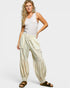 Woman wearing a white sleeveless top and beige patterned pants on a white background
