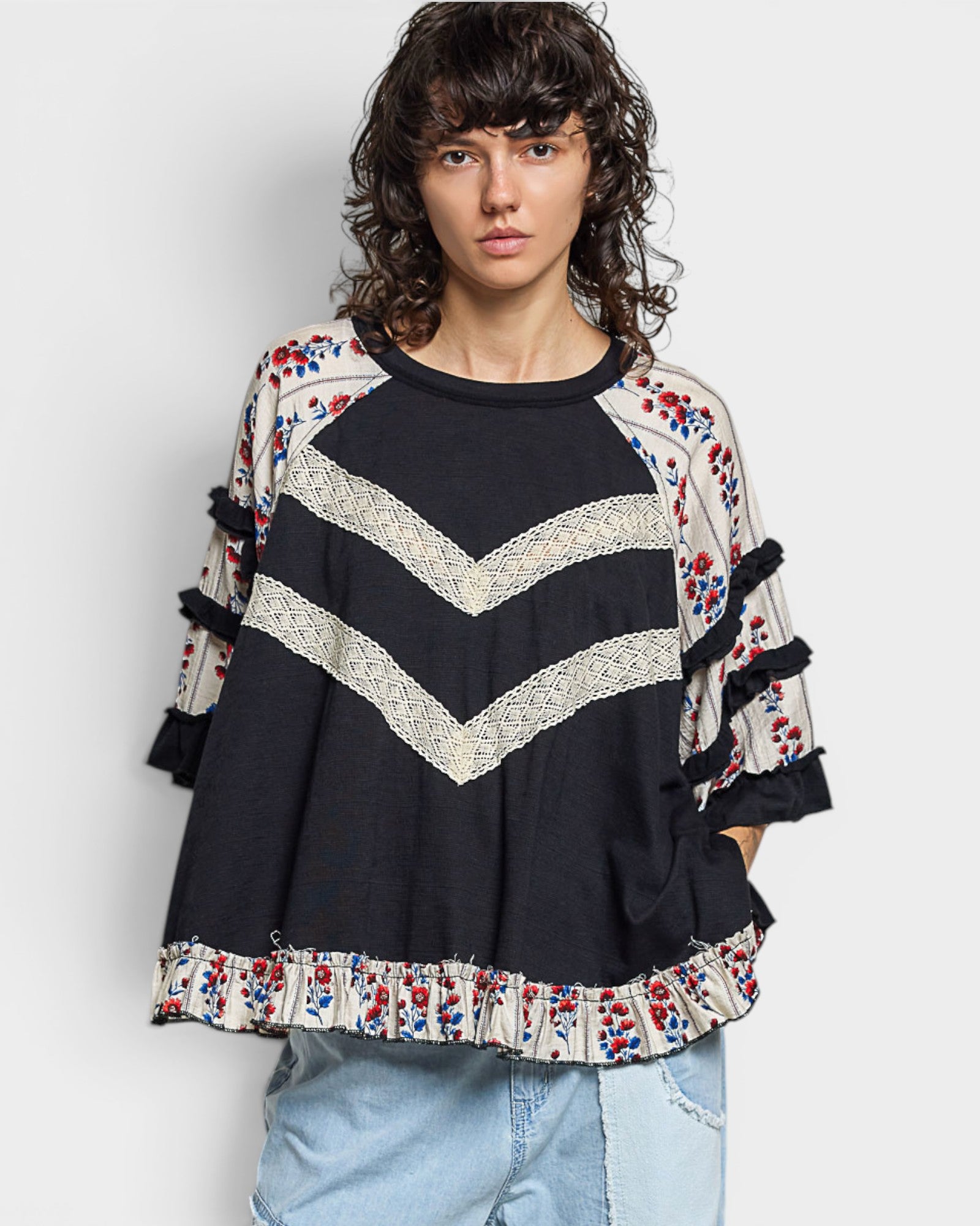 Woman wearing a black sweater with colorful patterns on a plain background