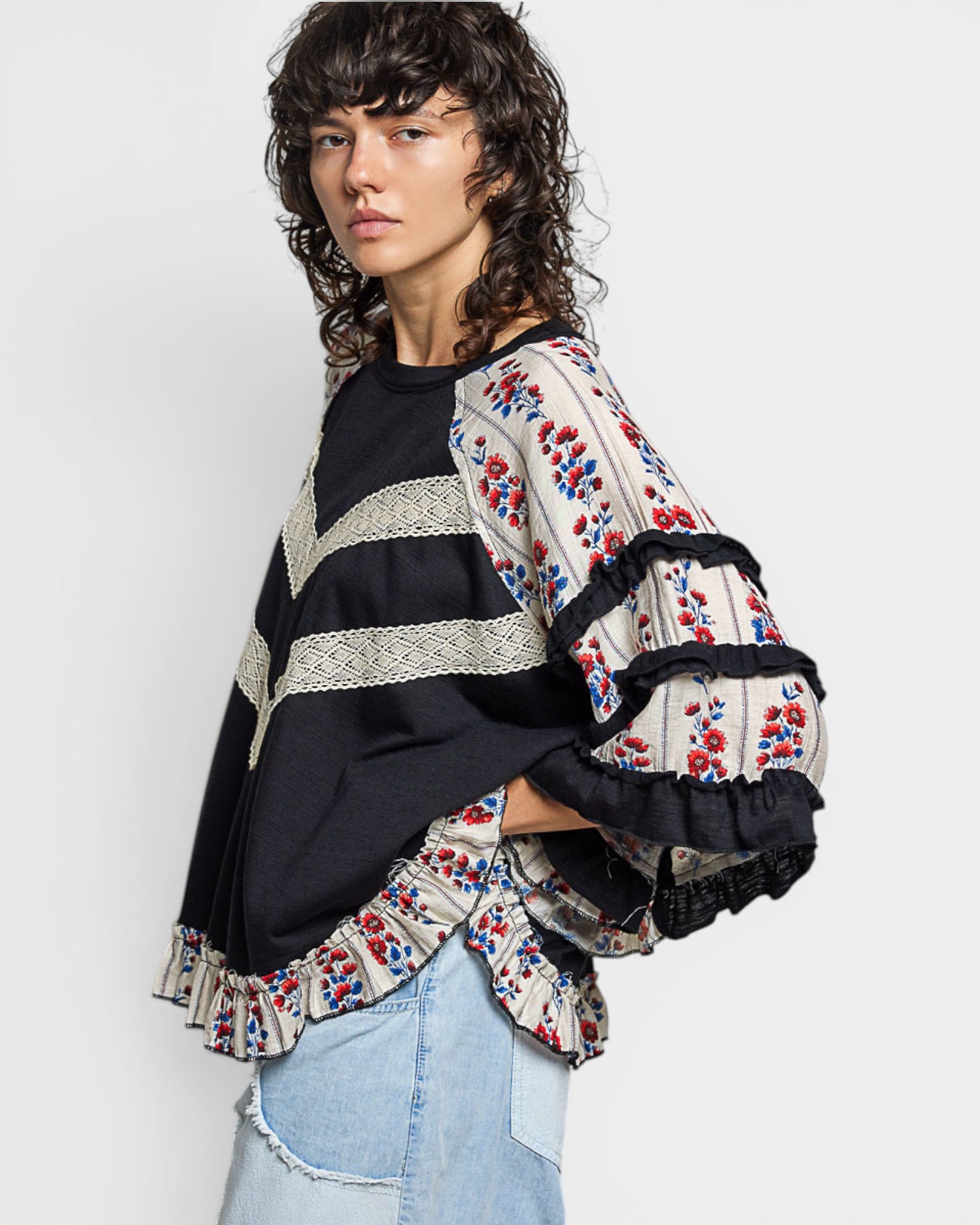Woman wearing a black top with a colorful embroidered jacket on a white background