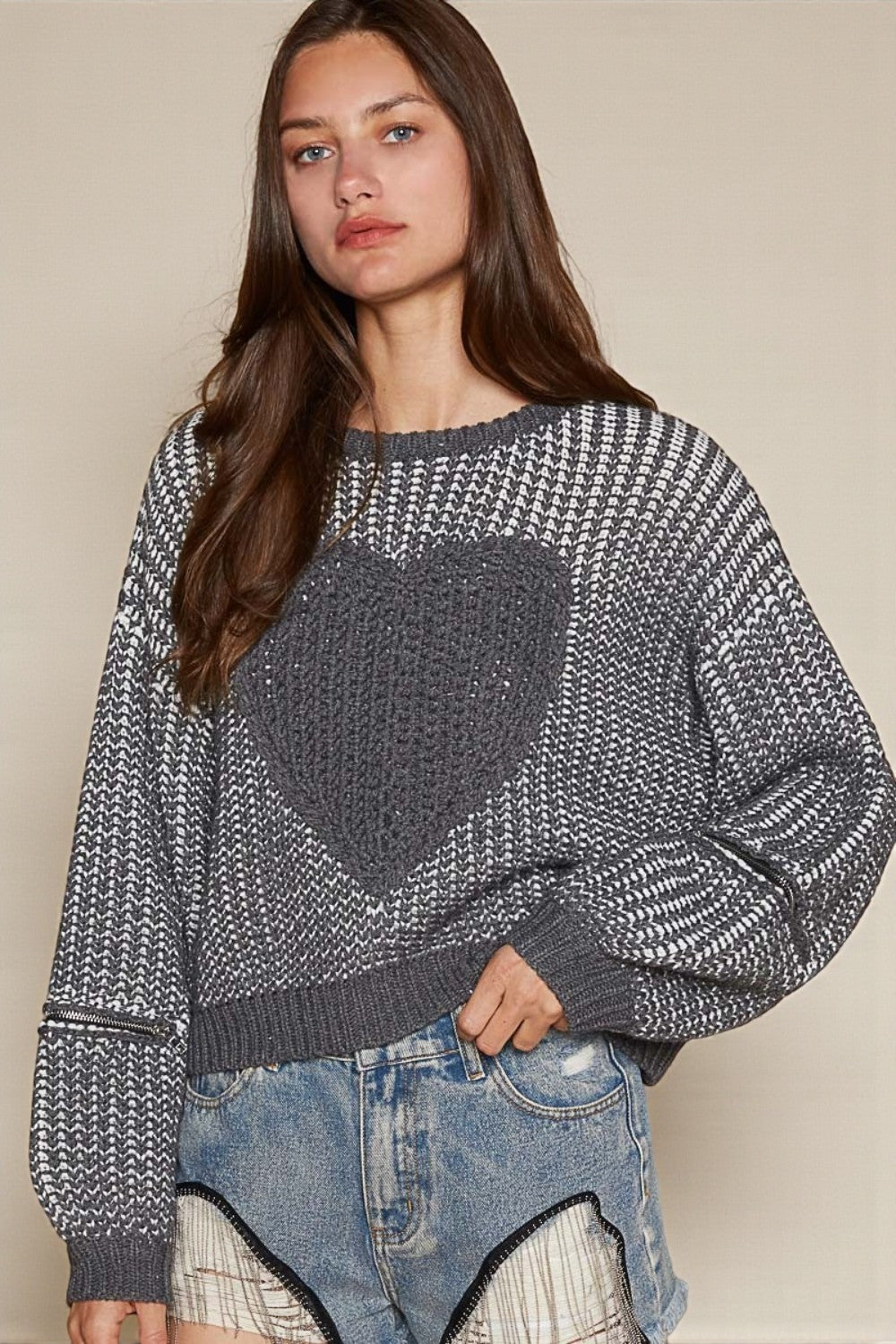 Woman wearing a patterned sweater and denim jeans against a beige background