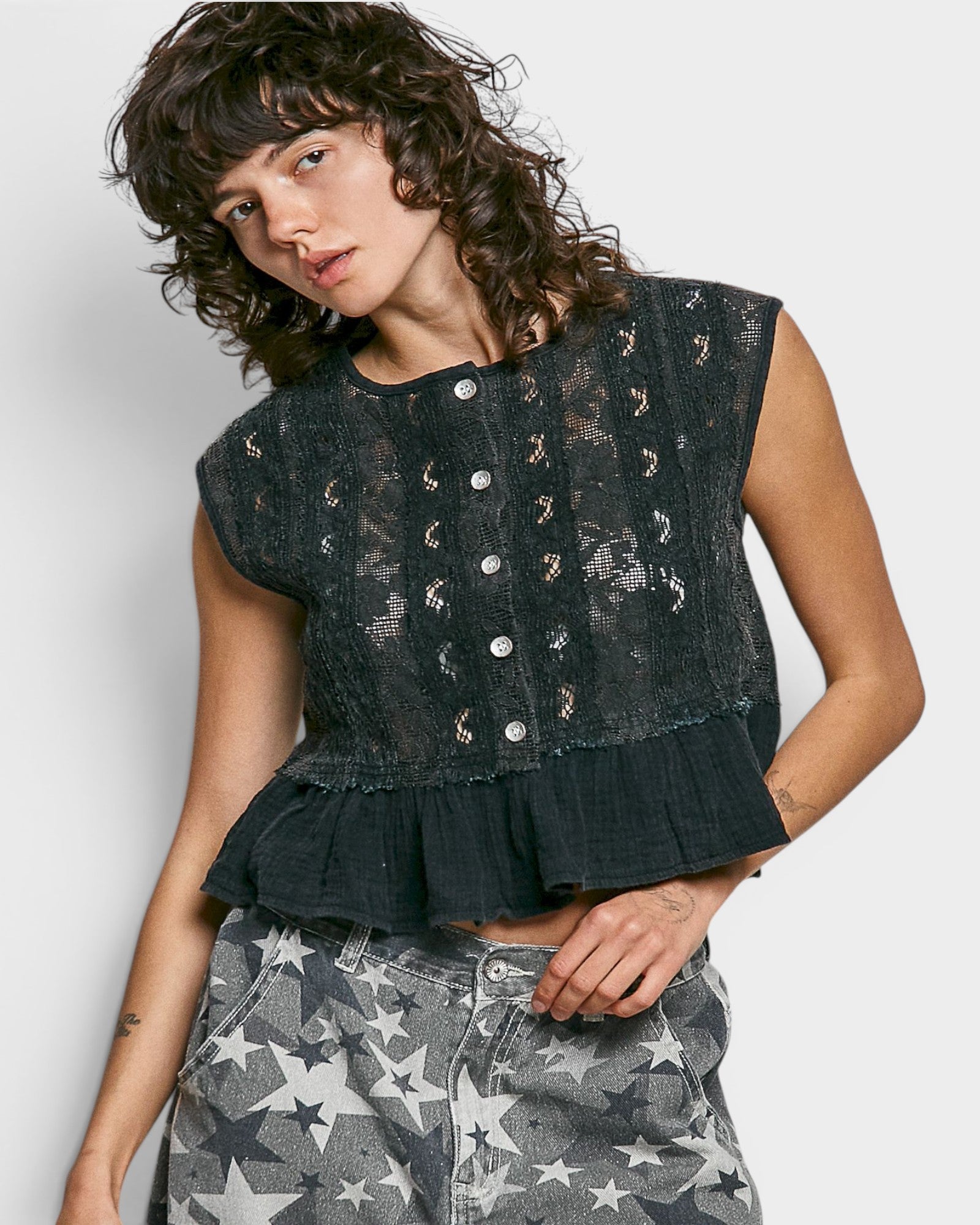 Woman wearing a black patterned top with a white background