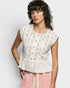 Woman wearing a floral peplum top and pink pants against a white background