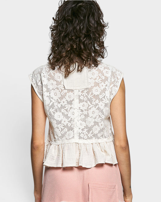 Person wearing a white lace top with a plain background