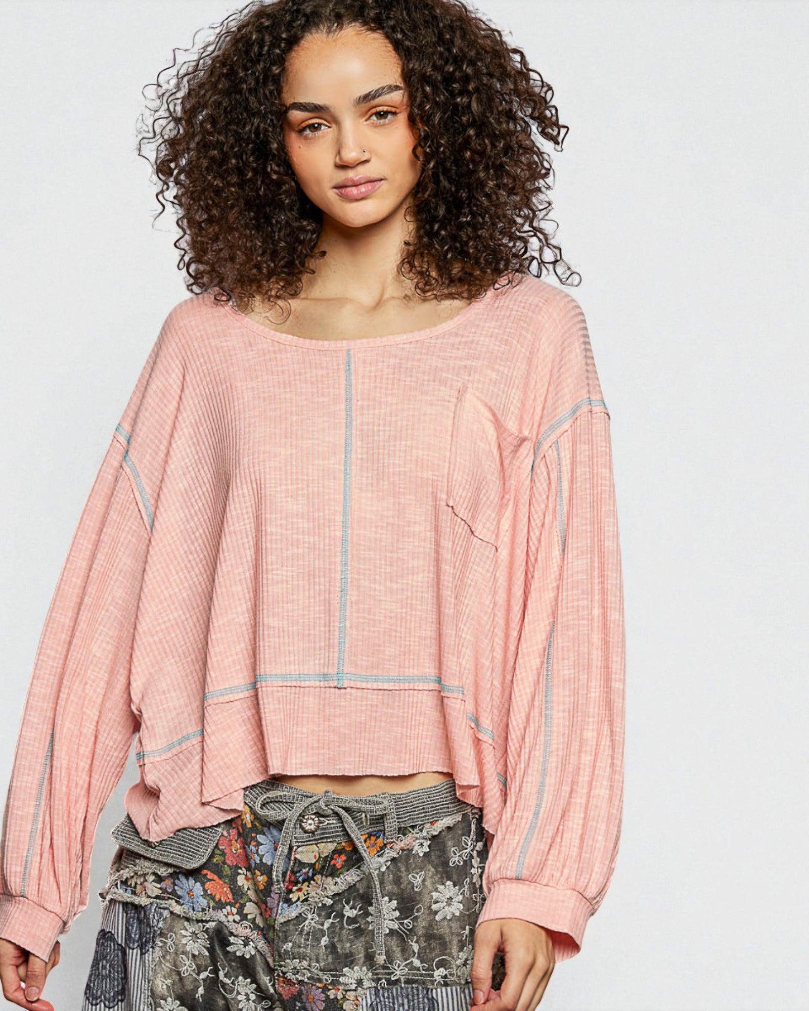 Woman wearing a pink textured top with a plain background