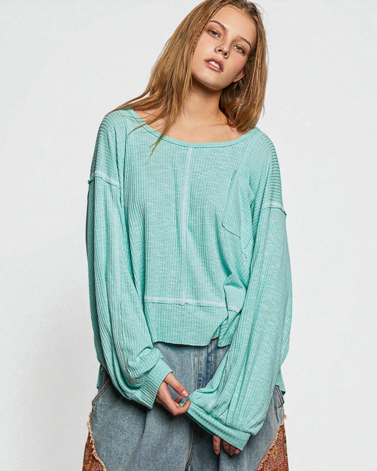 Woman wearing a light blue ribbed sweater on a white background