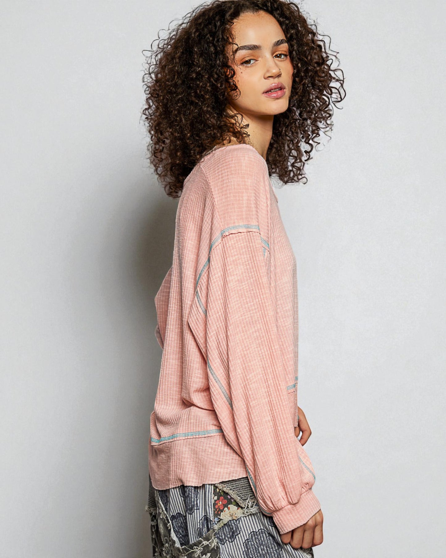 Woman wearing a pink textured sweater against a plain background