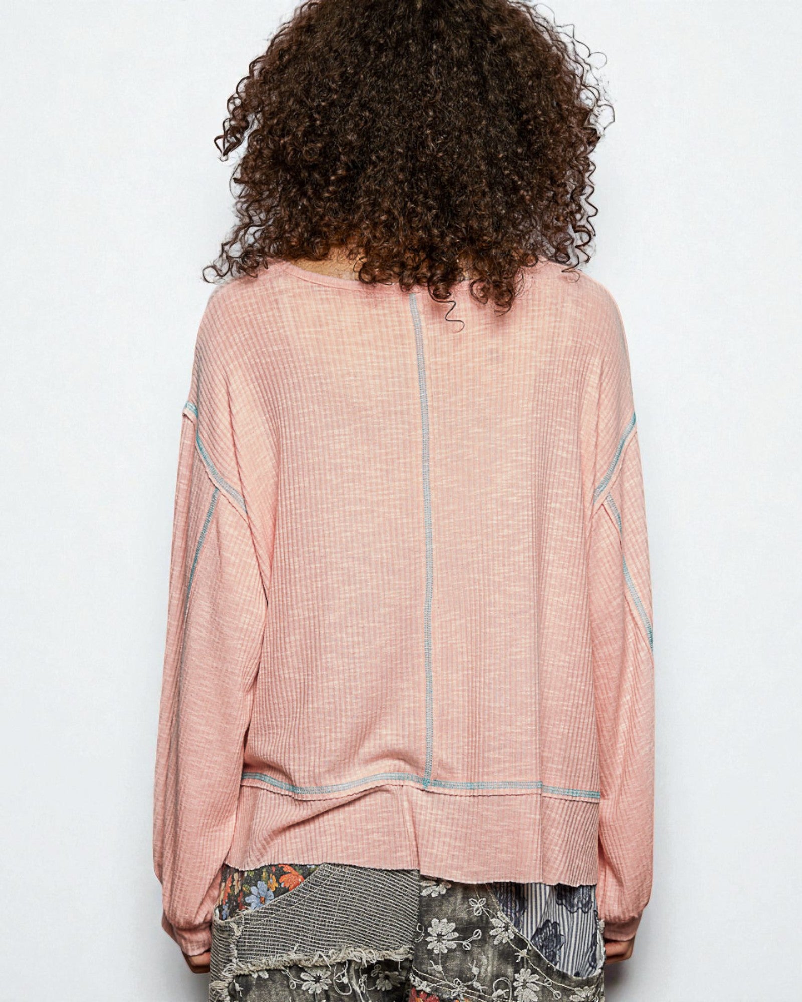 Person wearing a pink textured top with a white background