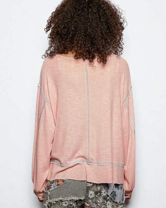 Person wearing a pink textured top with a white background