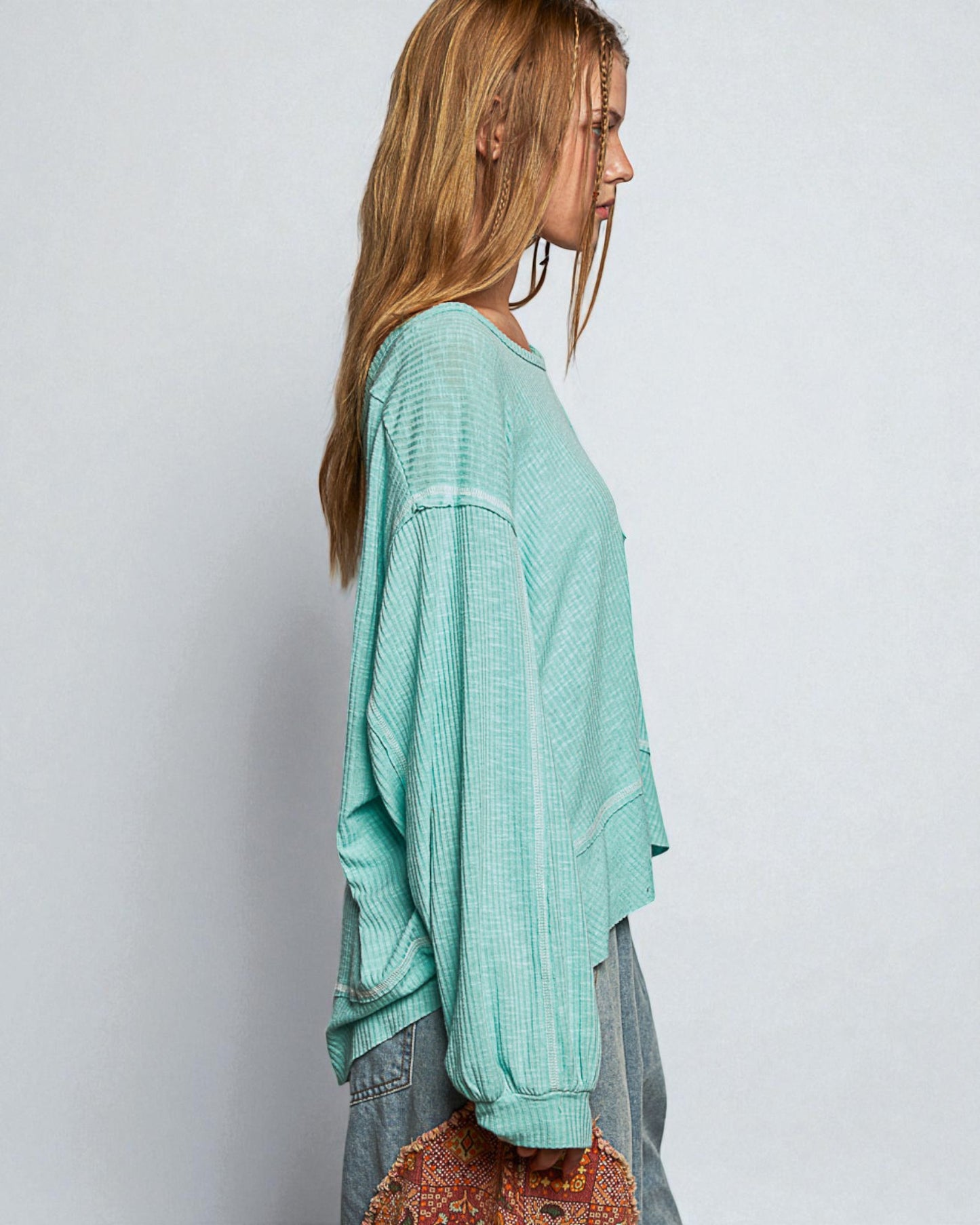 Woman wearing a light blue sweater and jeans against a plain background