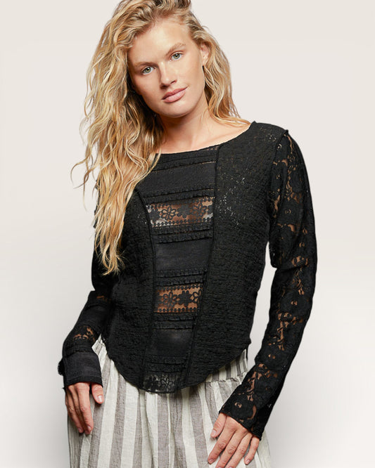 Woman wearing a black lace top with a plain background