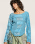 Woman wearing a blue textured top with a neutral background