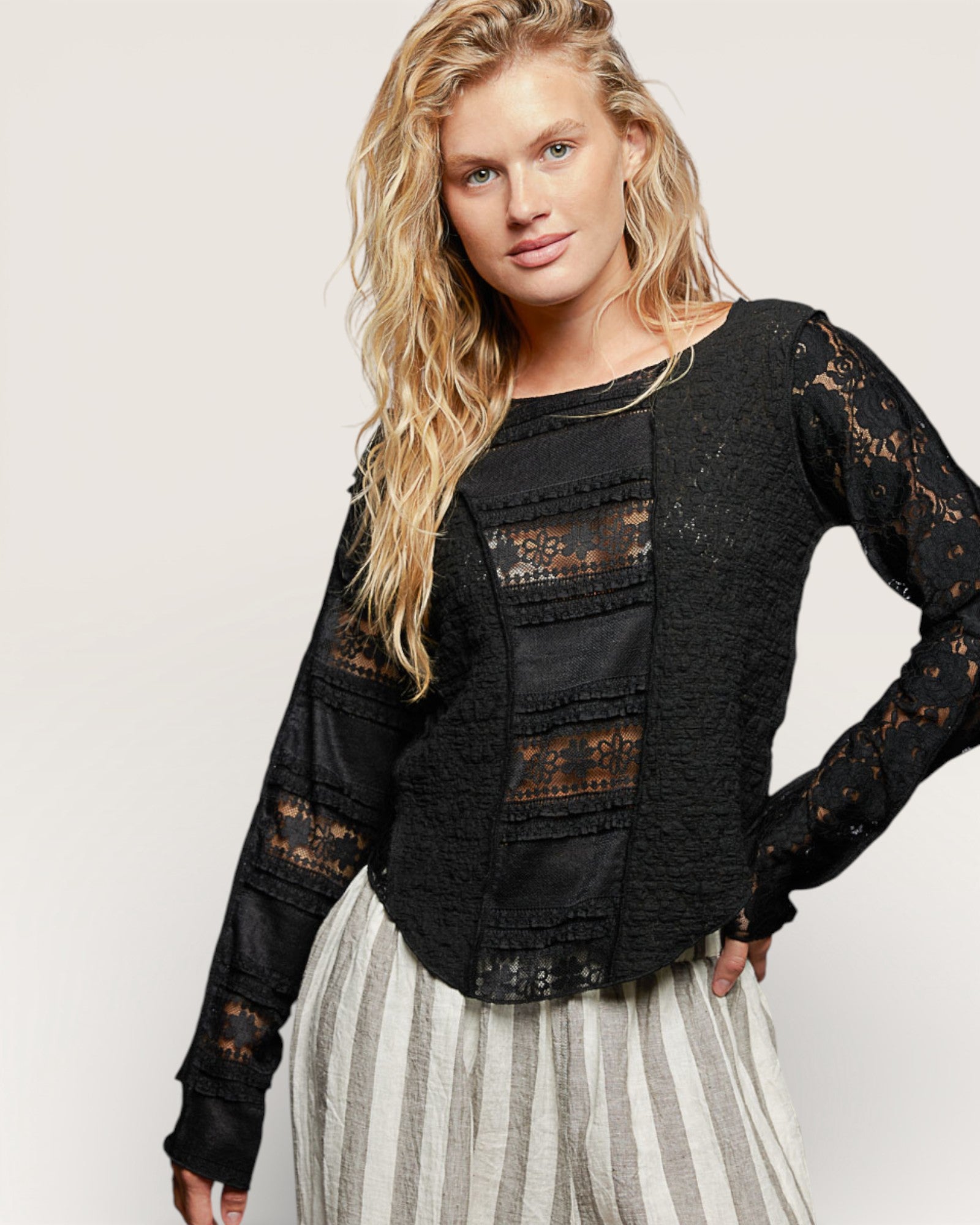 Woman wearing a black lace top with a plain background