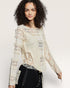 Woman wearing a patterned blouse with long sleeves on a plain background