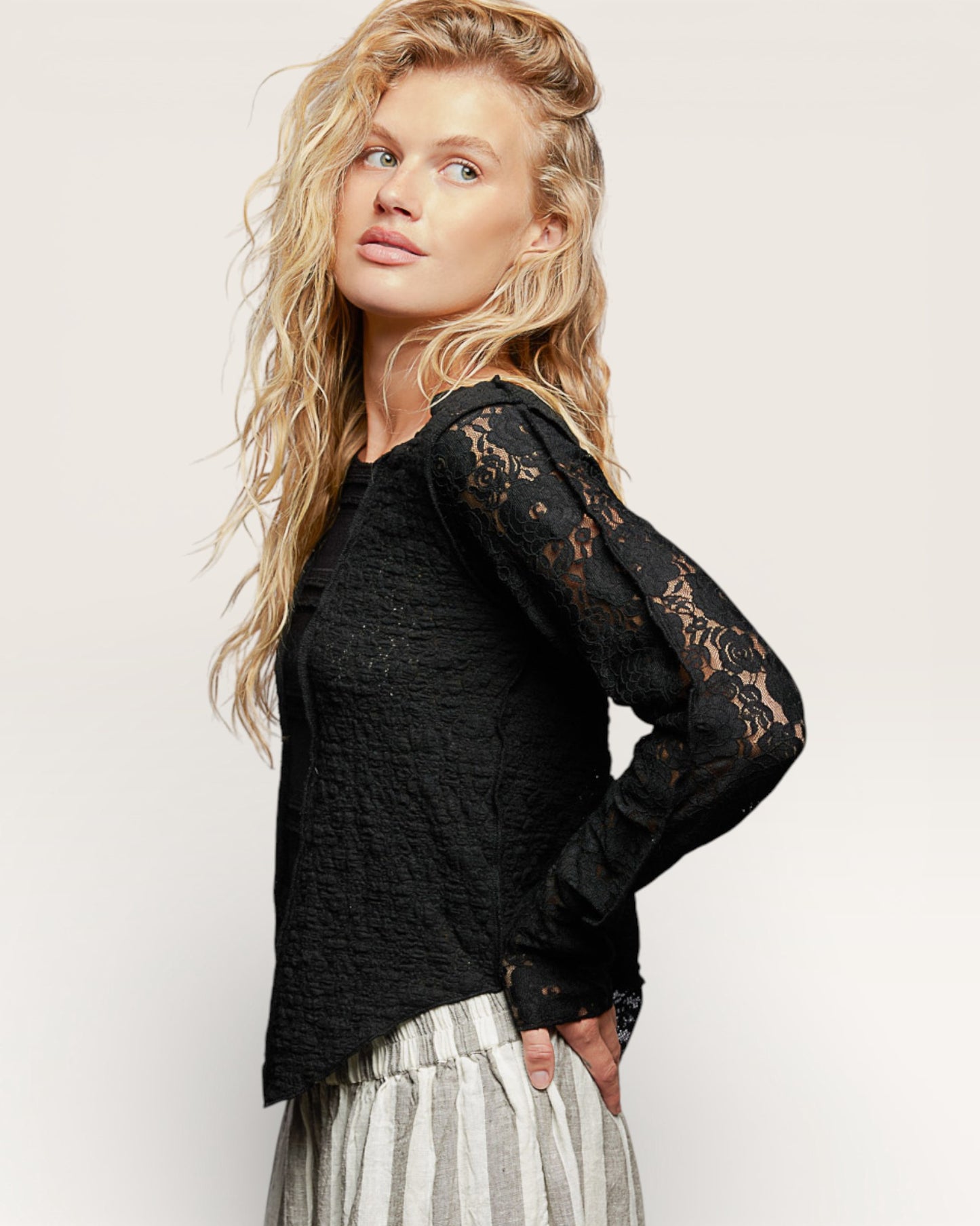 Woman wearing a black lace top with sheer sleeves on a white background