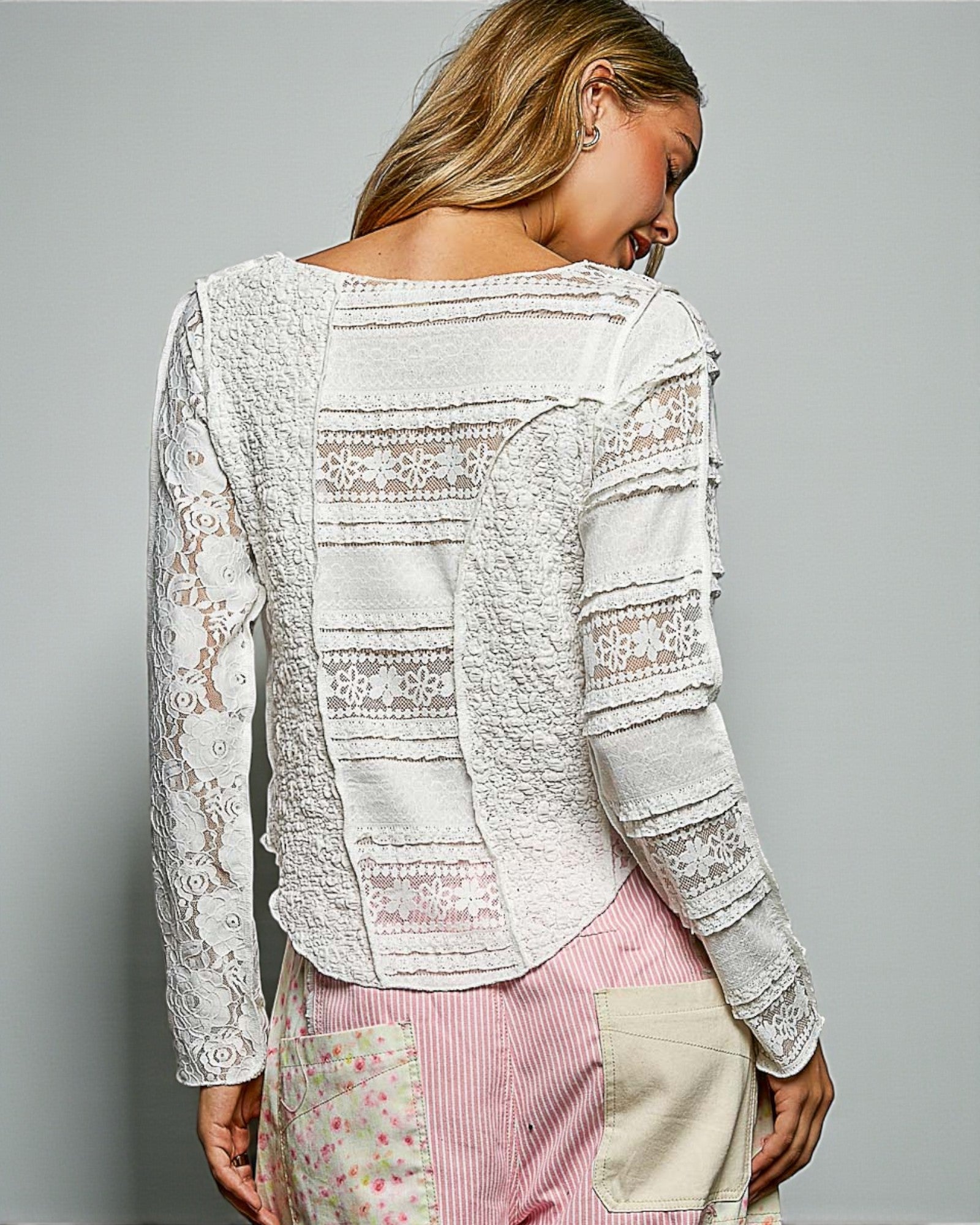 Woman wearing a white lace top with a gray background