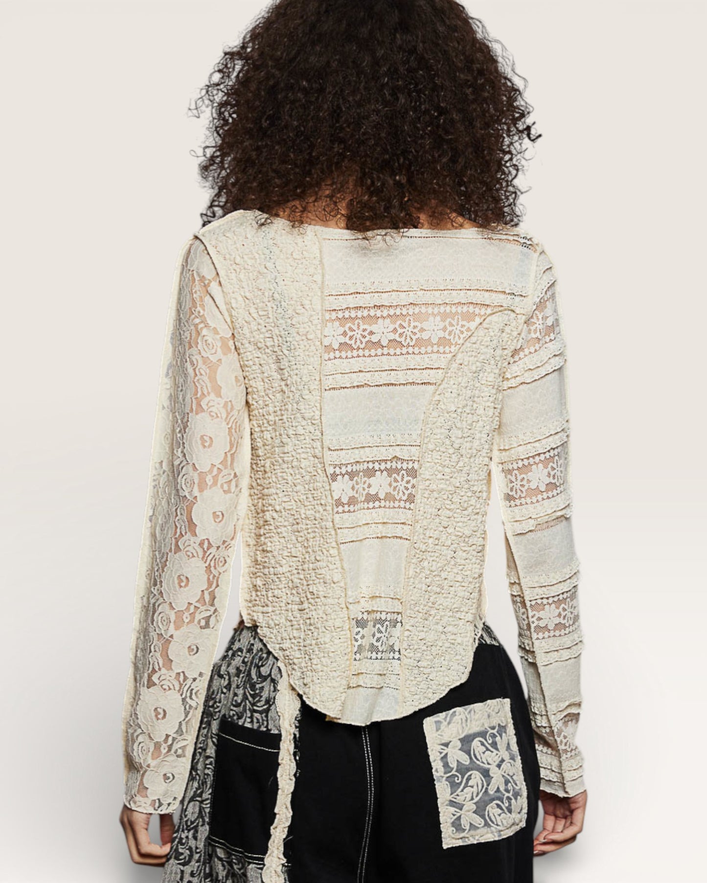 Person wearing a light-colored lace top with a plain background