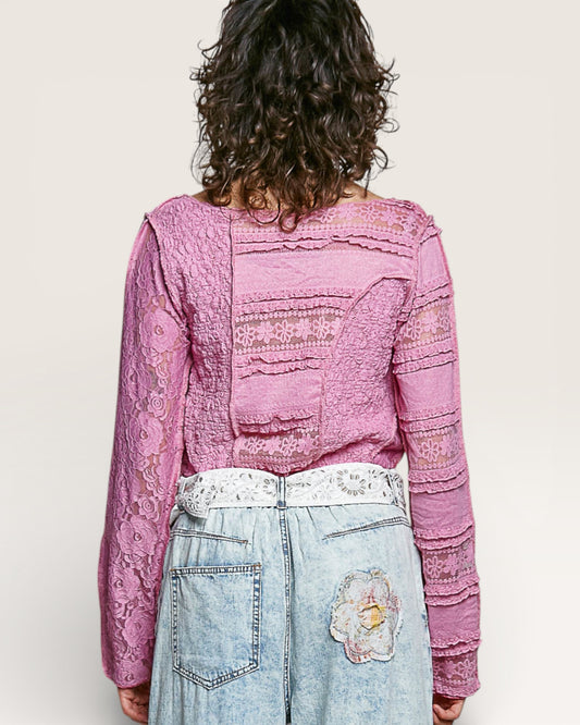 Person wearing a pink lace top and light blue jeans with a white background