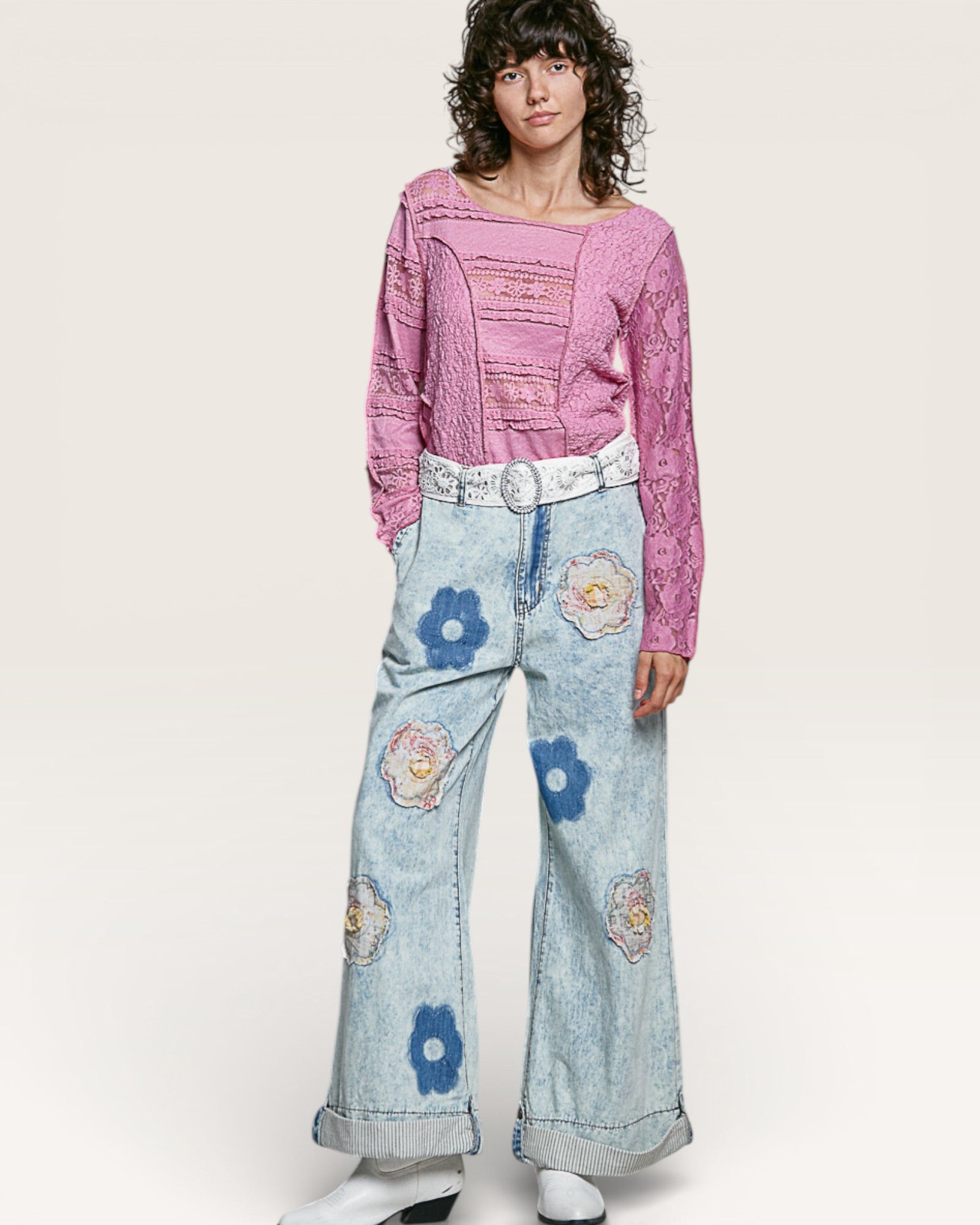 Person wearing a pink top and floral jeans on a white background