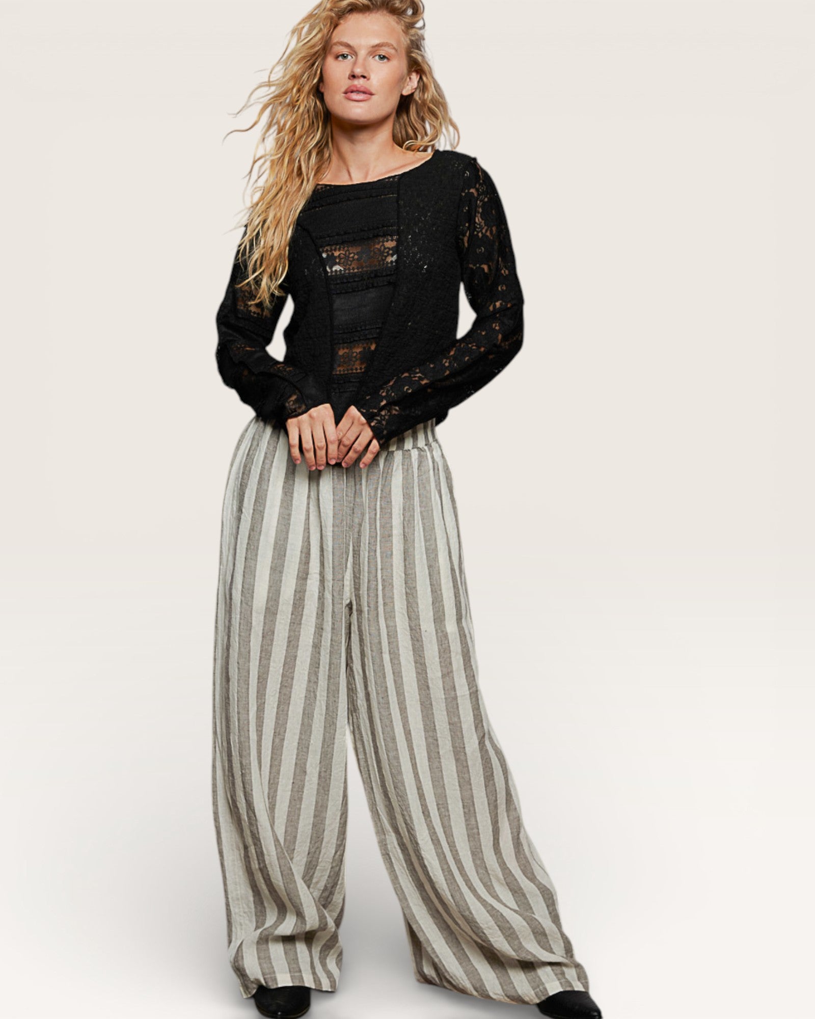 Woman wearing a black lace top and striped pants on a white background