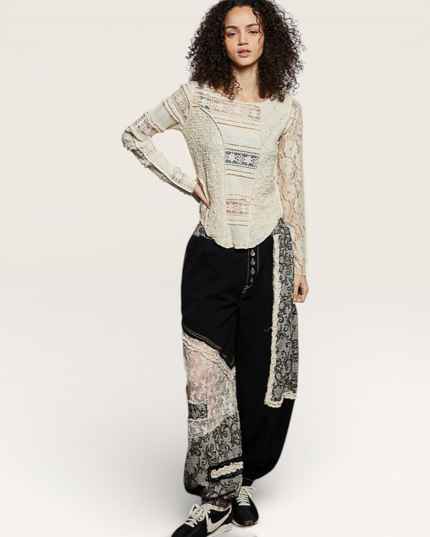 Woman wearing a long, patterned cardigan over a top with black pants on a white background