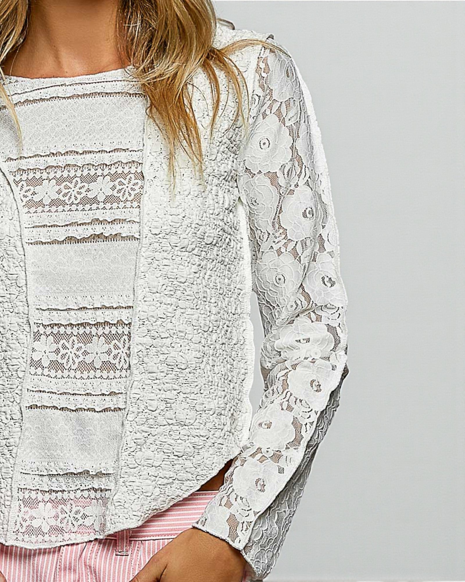 White lace long-sleeve top on a plain background