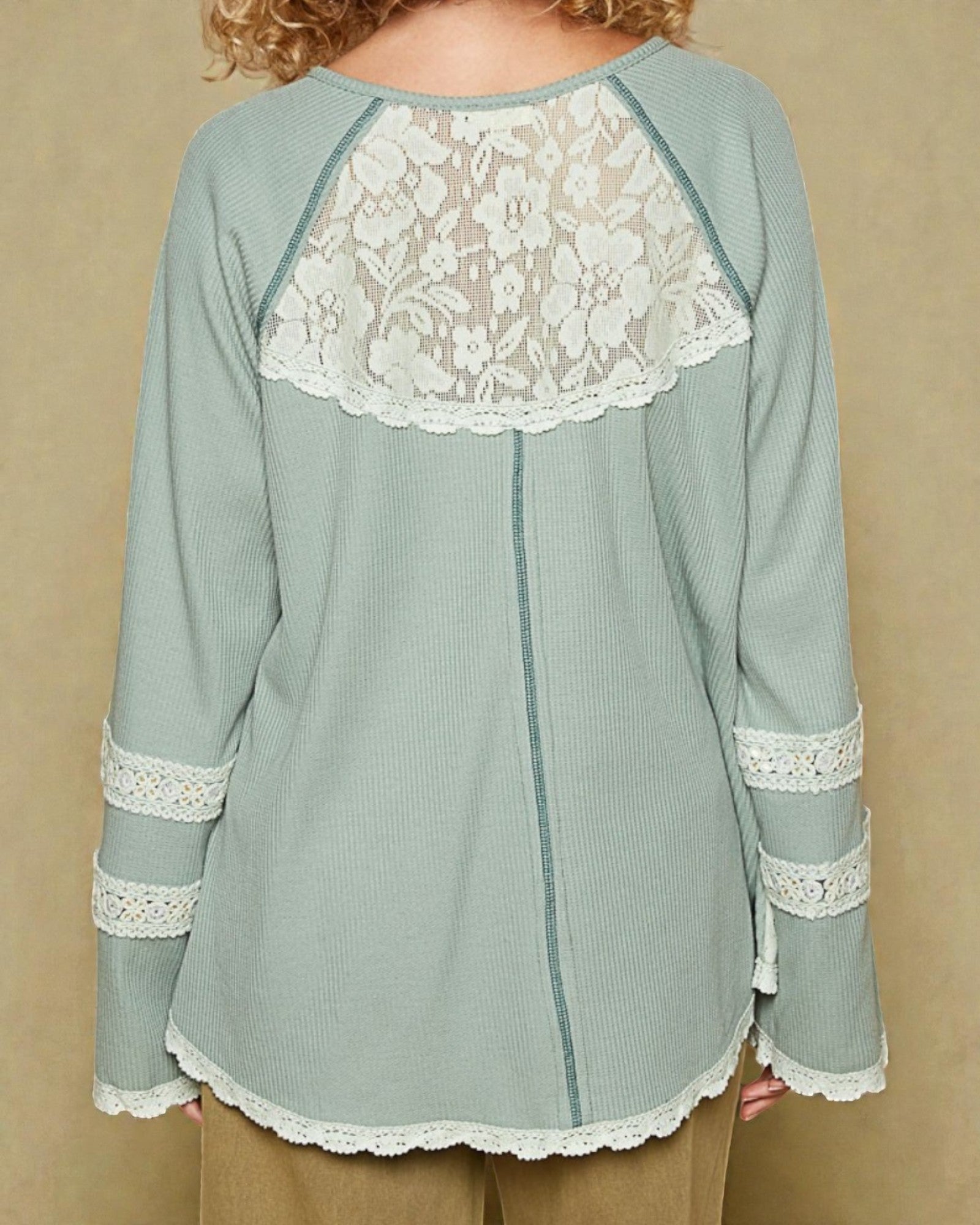 Light blue long-sleeve top with lace details on a beige background