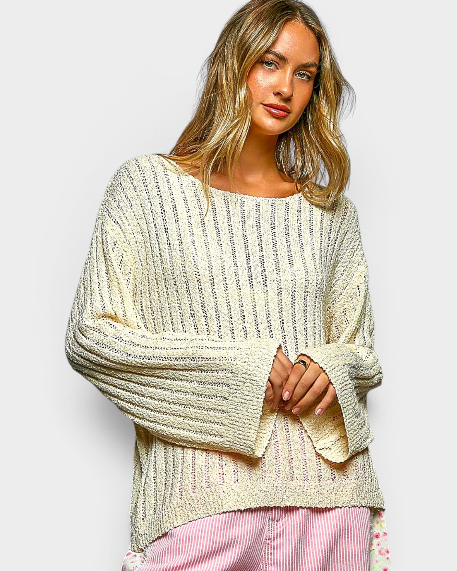 Woman wearing a cream-colored sweater with a plain background