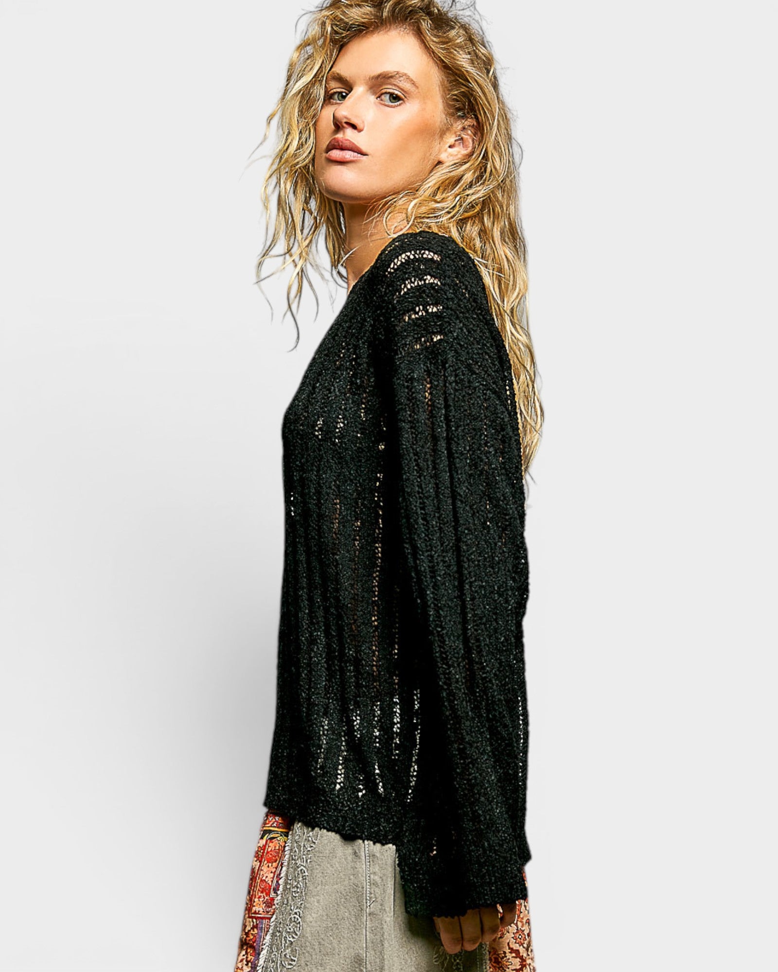 Woman wearing a black sequin cardigan on a light gray background