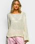 Woman wearing a light-colored knit sweater and pink pants against a plain background