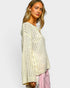 Woman wearing a light-colored knit sweater and pink pants on a plain background