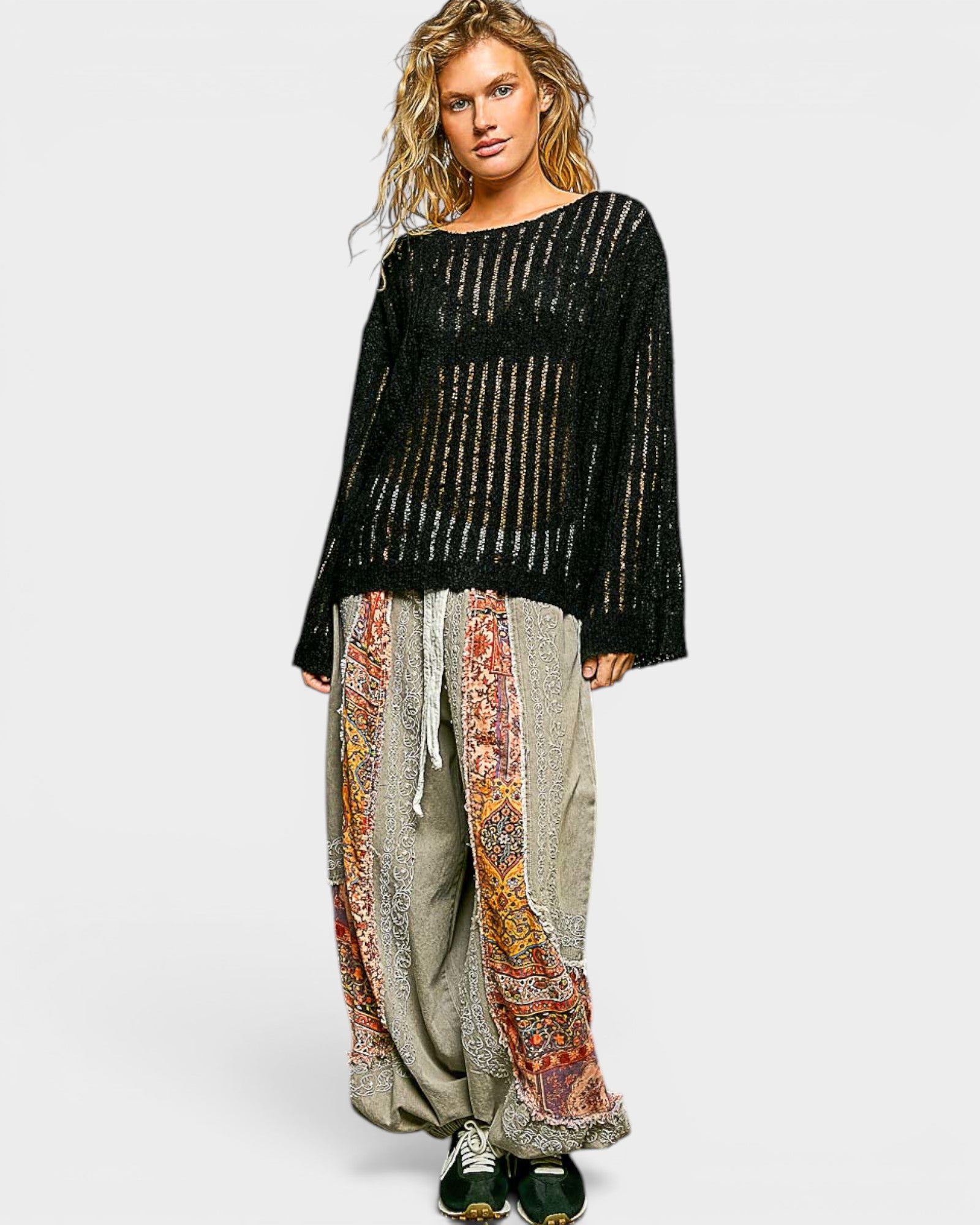 Woman wearing a black patterned top and colorful pants on a white background