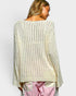 Woman wearing a loose-fitting beige knit sweater with a plain background