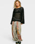 Woman wearing a black patterned top and colorful pants on a white background