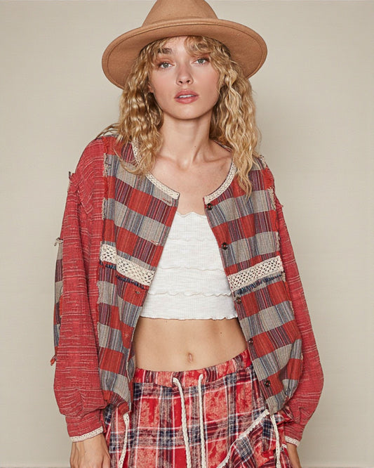 Woman wearing a red plaid shirt and pants with a beige hat on a plain background