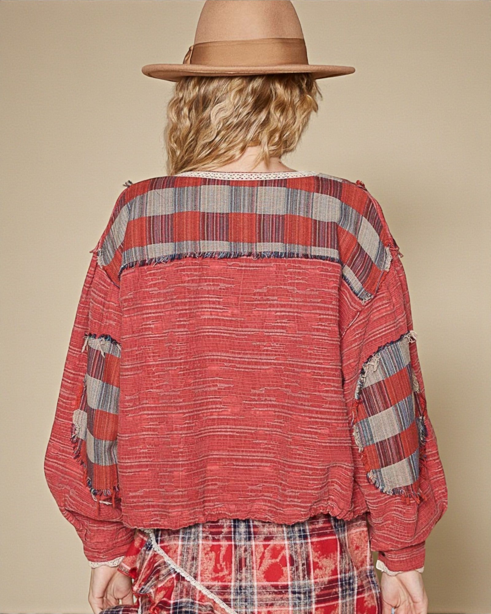 Person wearing a red plaid shirt and hat on a beige background