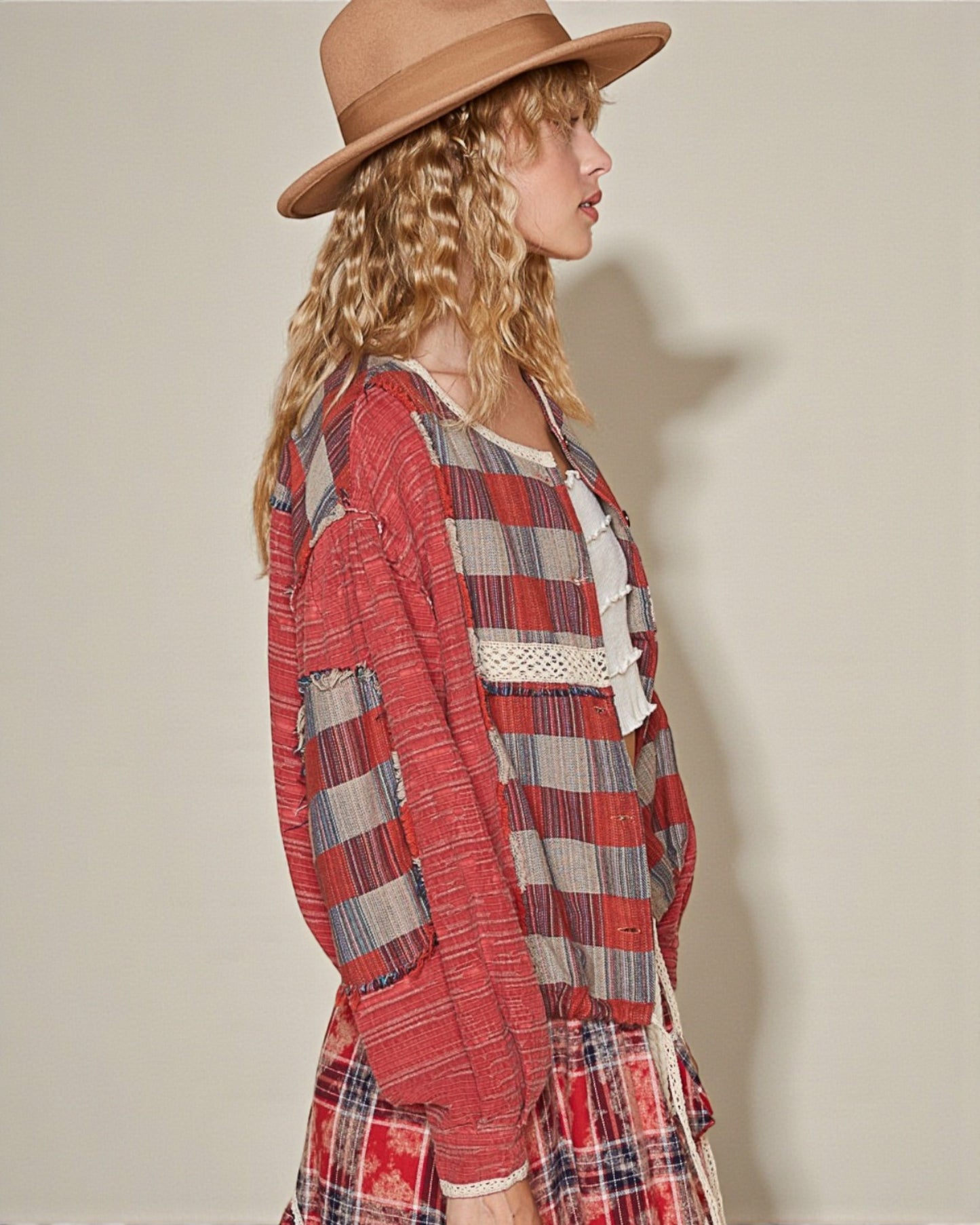 Woman wearing a red plaid dress and brown hat against a plain background