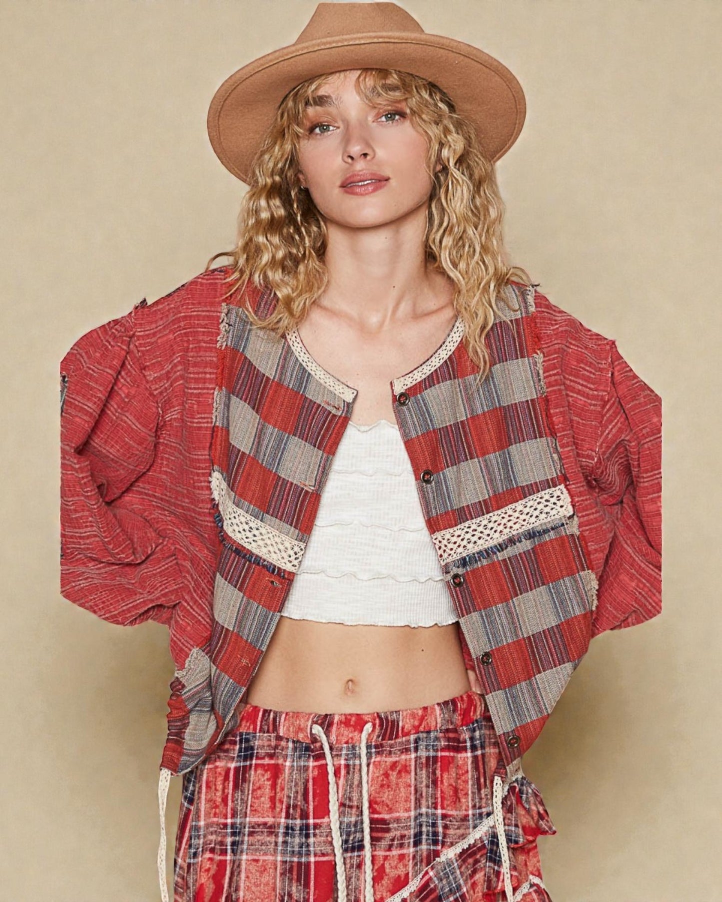 Woman wearing a red plaid jacket and pants with a beige hat on a beige background