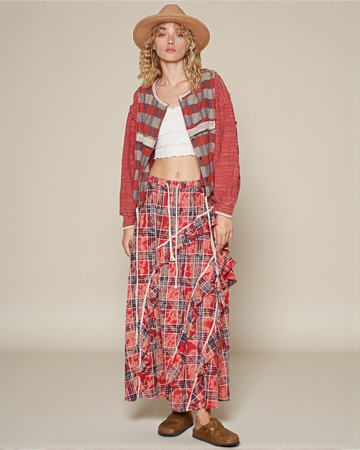 Woman wearing a plaid outfit with a hat on a plain background