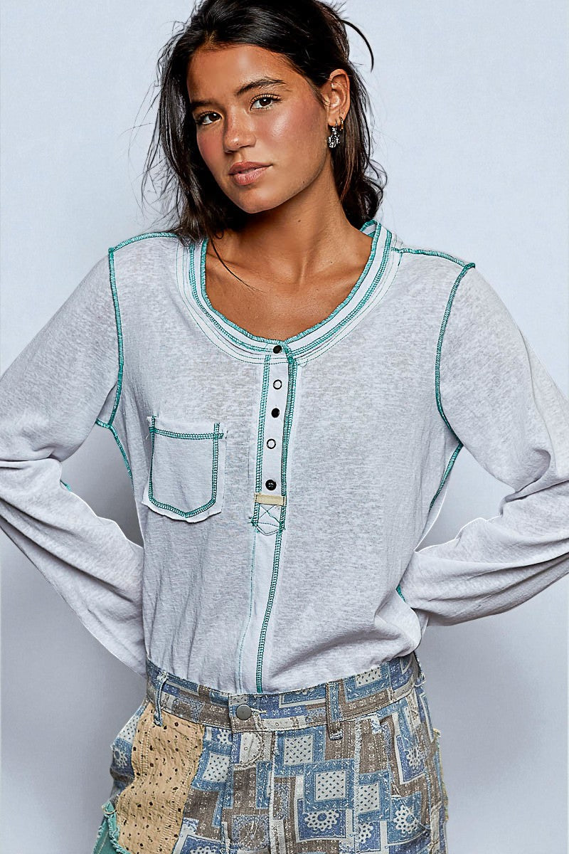 Woman wearing a light gray long-sleeve shirt with teal accents against a plain background