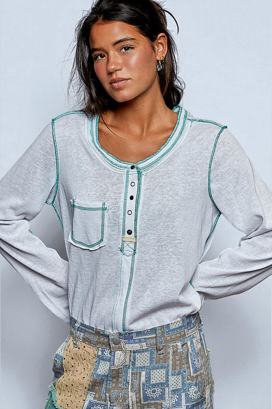 Woman wearing a light gray long-sleeve shirt with teal accents against a plain background