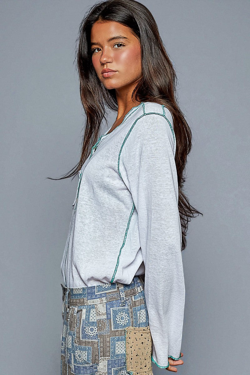 Woman wearing a light gray cardigan over a patterned dress against a gray background