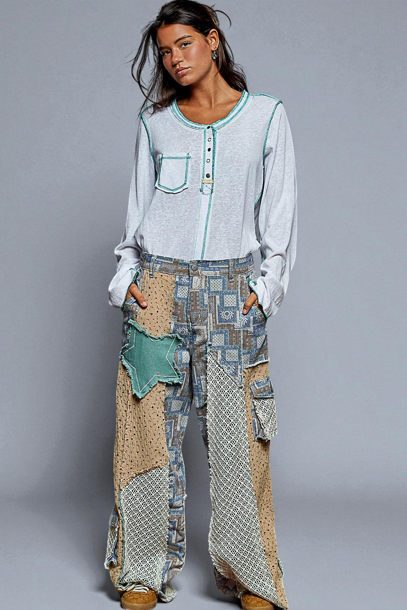 Woman wearing a light blue patterned shirt and patchwork pants on a gray background