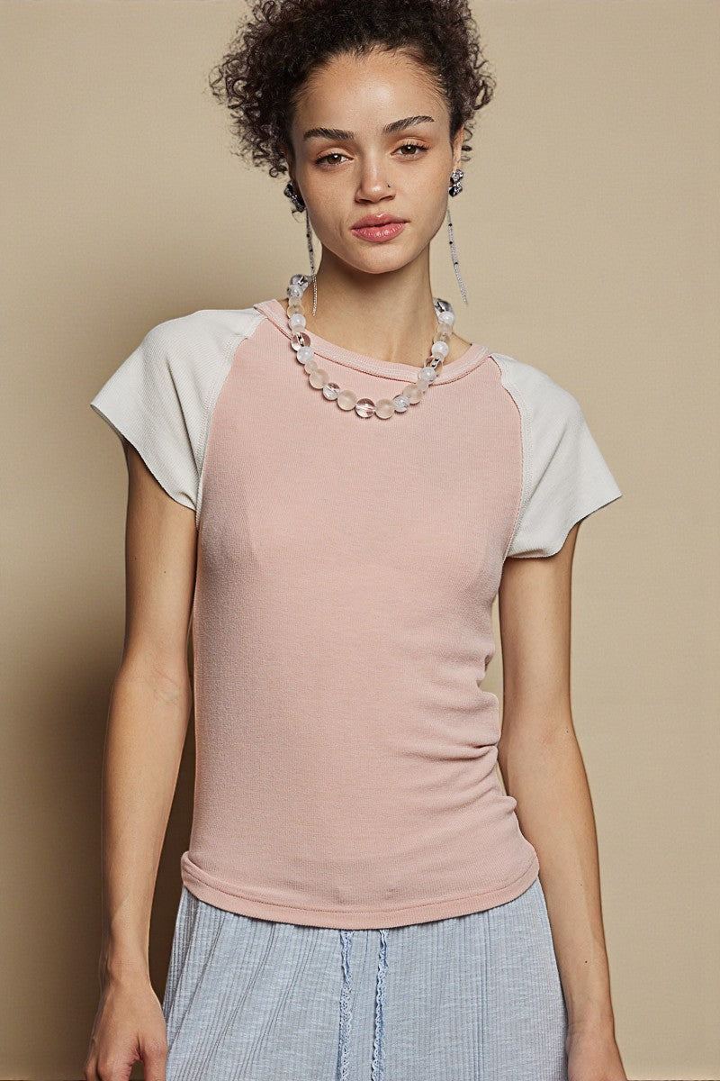 Woman wearing a pink and white baseball shirt with a beige background