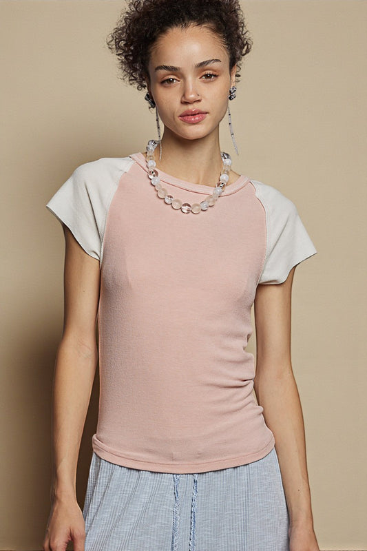 Woman wearing a pink and white baseball shirt with a beige background